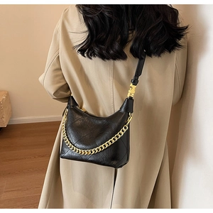 Close-up of quilted black shoulder bag with gold chain strap and smooth faux leather finish