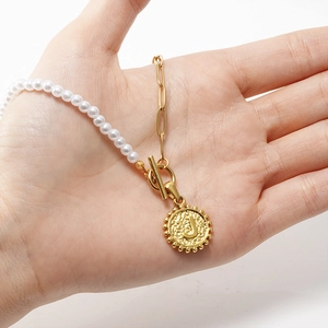 Vue détaillée du fermoir à bascule doré et du pendentif lettre J sur collier de perles