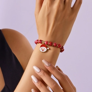 Detailaufnahme eines roten Weihnachts-Perlenarmbands mit einem Weihnachtsmann-Anhänger