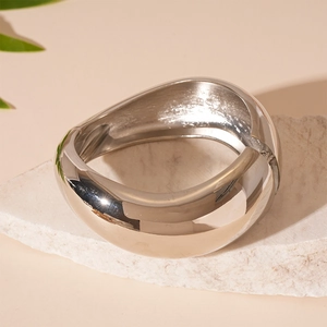 Detailed view of silver irregular geometric metal bangle resting on natural white stone