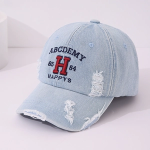 Detail of embroidered letters and vintage distressed ripped edges on denim baseball cap