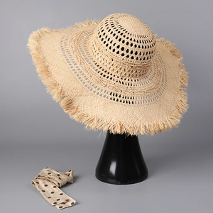 Detailed close-up of woven raffia sun hat with hollow patterns and frayed brim edges