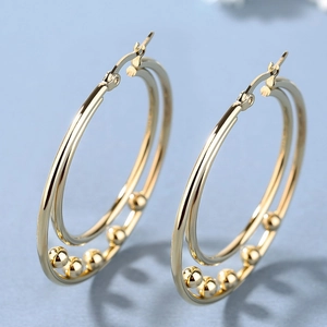 Fashion gold double hoop earrings with decorative metal beads on textured blue background