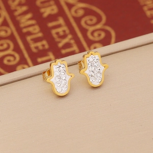 Detailed macro view of golden Hamsa earrings set with sparkling white rhinestones