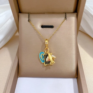 Detail of gold necklace with blue heart, plane and suitcase pendants in a jewelry box