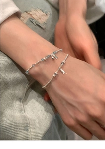 Detailed shot of ethnic pearl beaded bracelets with small silver fish charms on wrist