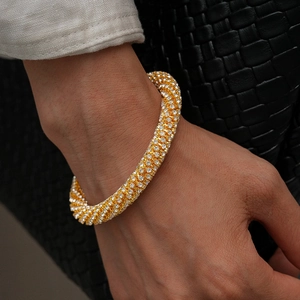 Gros plan d'un bracelet géométrique doré orné de strass portés par un mannequin