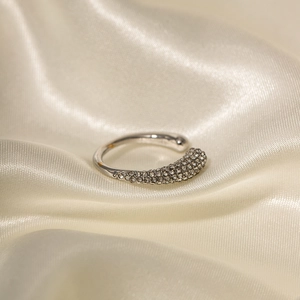 Close-up of silver open ring with pavé set white zircon on elegant cream satin fabric