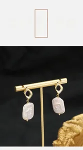 Detailed shot of natural baroque pearl earrings with golden geometric hooks on display
