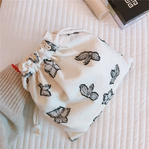 Detail of black butterfly embroidery on white linen drawstring storage bag pouch