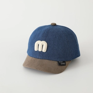 Dettaglio cappellino baseball neonato con lettera M ricamata e visiera marrone scuro