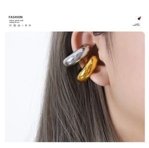 Detailed view of large gold and silver polished metal ear cuffs worn on the ear
