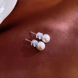 Macro shot of minimalist grey pearl studs with silver needles on dark silk fabric