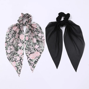 Detail of pink floral and solid black knotted hair scrunchies with long silk streamers