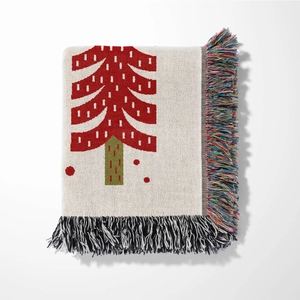 Close-up of the woven cotton texture and colorful tassels on the Christmas tree blanket
