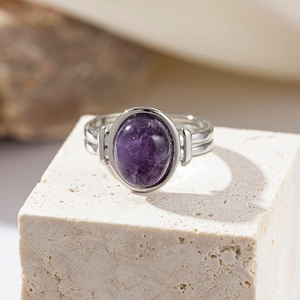 Detailed close-up of a purple oval amethyst ring on a minimalist stone display stand