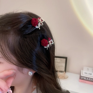 Macro detail of red flocked rose hair clip with rhinestone heart and golden metal claw
