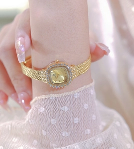 Close-up of golden square dial watch with rhinestones on a female wrist in lace