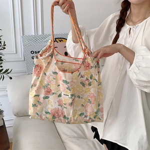 Detail of floral tote bag showing orange checkered handles and drawstring closure