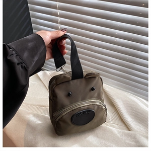 Detail view of army green nylon dog-shaped handbag with premium metal zipper and ear accents