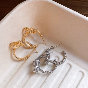 Classic gold and silver knotted C-shaped hoop earrings with woven metal texture
