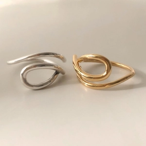 Detailed view of minimalist curved open rings in polished silver and gold metal finishes