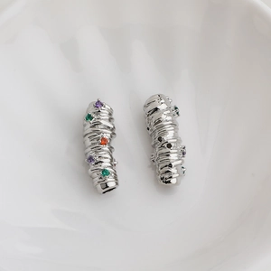 Macro shot of silver metal jewelry spacers with twisted texture and colored gemstones