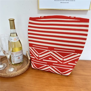 Close-up of red and white knitted tote bag texture on a rustic wooden table