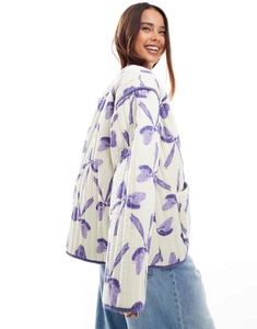 Detail of loose-fit white quilted jacket with purple bow prints and side pockets