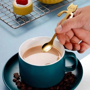 Golden cartoon cat coffee spoon hanging on green mug for creative dessert stirring