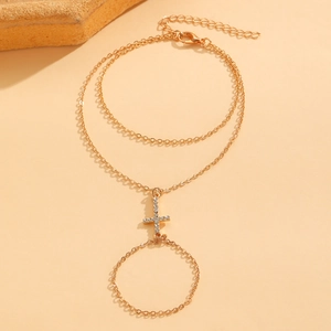 Detailed view of a gold cross ring bracelet with sparkling rhinestones on hand chain