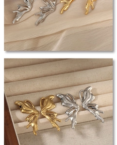 Close-up of butterfly wing earrings in gold and silver finish on silk and velvet