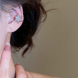 Detail of silver flower ear cuff with zircon and pearl on a person's ear cartilage