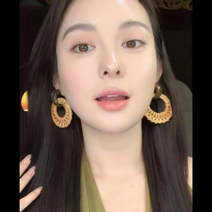 Gros plan d'un mannequin portant des boucles d'oreilles en raphia tressé naturel