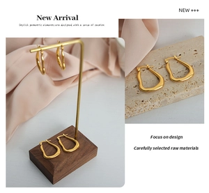 Detailed view of gold irregular geometric hoop earrings on minimalist display props