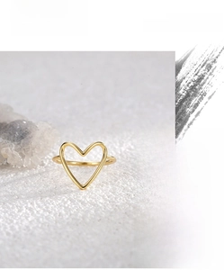 Macro shot of 18K gold plated heart hollow ring standing on white textured surface