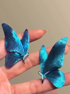 Detail of butterfly earring with blue-green gradient wings and micro-pave diamonds