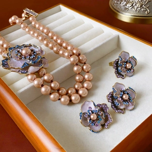 Close-up of vintage jewelry set with purple enamel flower pendants and pearl necklace