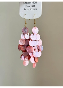 Close-up of pink shell tassel earrings with copper hooks and multilayered iridescent petals