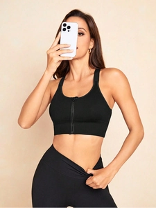 Detail of black sports bra with front zipper and matching high-waist leggings on model