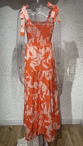 Detail of orange leaf print dress featuring ruched strapless bodice and tie-up shoulder straps