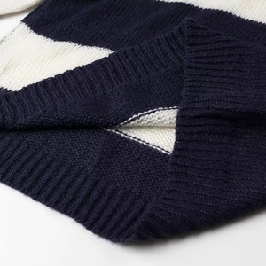 Close-up of ribbed cuffs on a navy and white striped knit sweater showing wool texture
