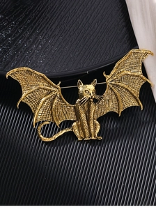 Detailed close-up of a vintage gold-toned winged cat brooch on a black textured background