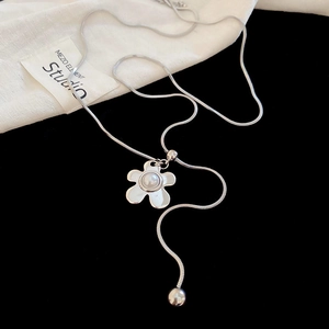 Detail of silver wavy flower pendant with a pearl center on a delicate snake chain