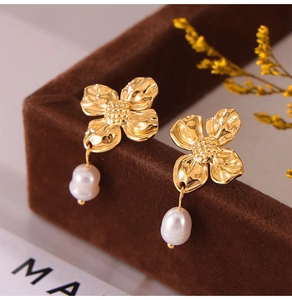 Detailed macro of golden petal earrings with freshwater pearls on brown velvet jewelry box