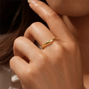 Close-up of minimalist 18K gold plated ring worn on index finger with smooth metallic finish