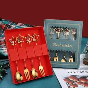 Detailed close-up of golden Christmas spoons with cartoon charms in a festive gift box