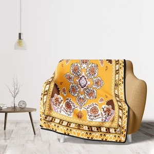 Yellow mandala flannel throw blanket with ethnic floral pattern draped on a modern sofa
