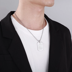Detailed close-up of a silver military tag necklace with lotus and heart sutra carving