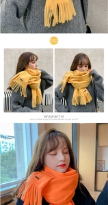 Detail of ginger yellow cashmere-like scarf with long tassels and a minimal woven label
